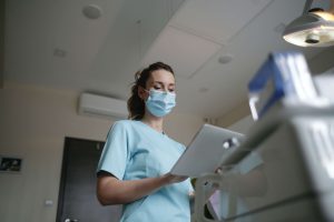 A female nurse or doctor reviews a patient's chart in a hospital room