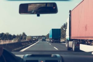 A car attempts to pass two semi trucks in the far left lane on the freeway